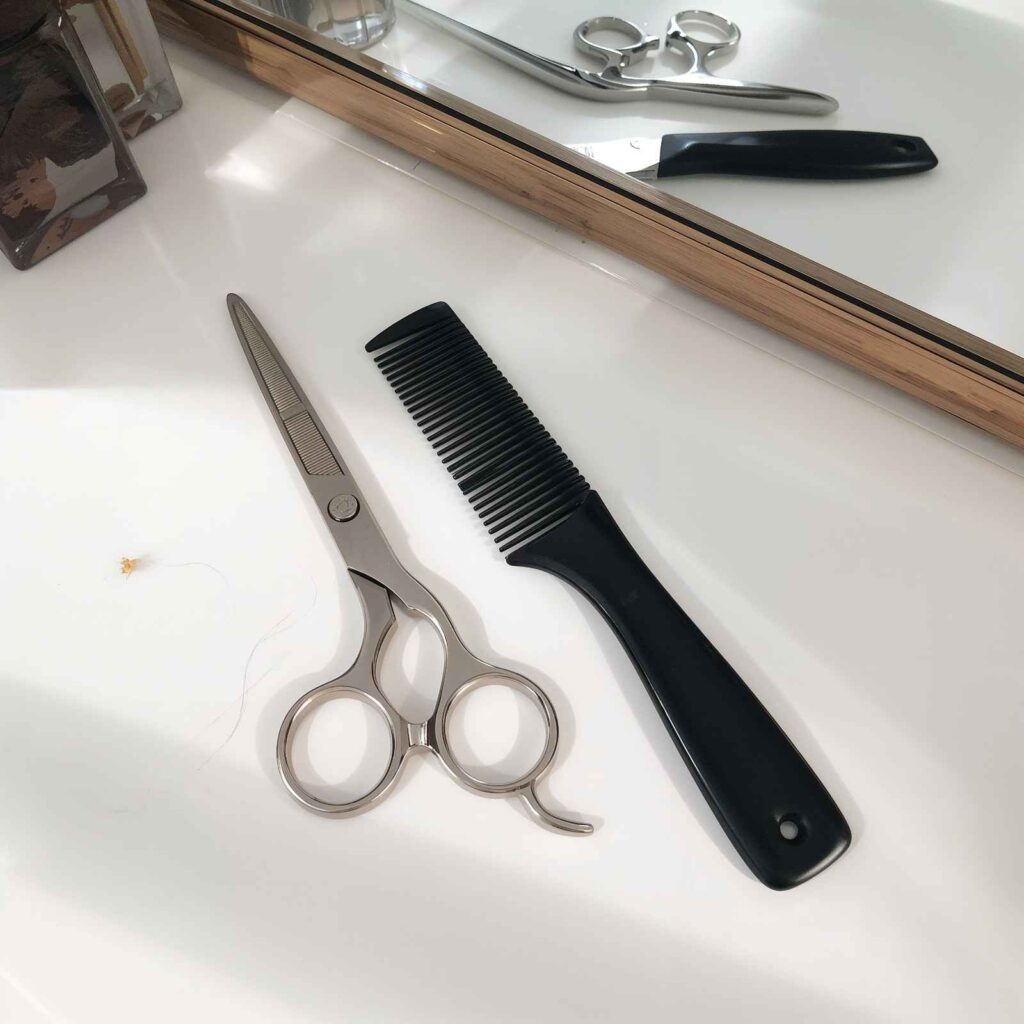 Essential tools for cutting curtain bangs at home including scissors and comb.