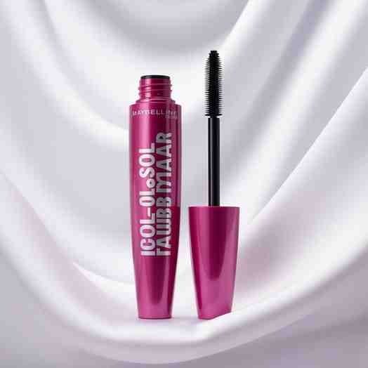 Holding Maybelline Colossal Bubble Mascara tube in hand against white background